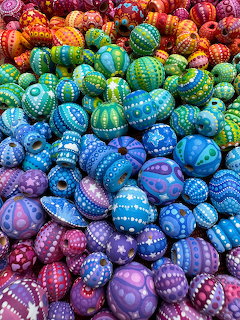 Colorful hand-painted rocks with dot mandala patterns arranged in rainbow gradient from red to purple