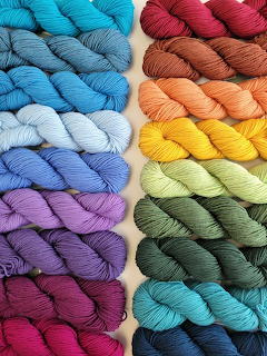 Neatly arranged colorful yarn skeins in multiple rainbow hues displayed in vertical rows