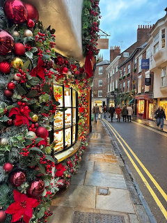 Christmas garlands and red ornaments on a shopfront beside a wet street in York