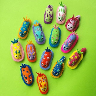 Colorful handmade nudibranch figures arranged on a bright green background