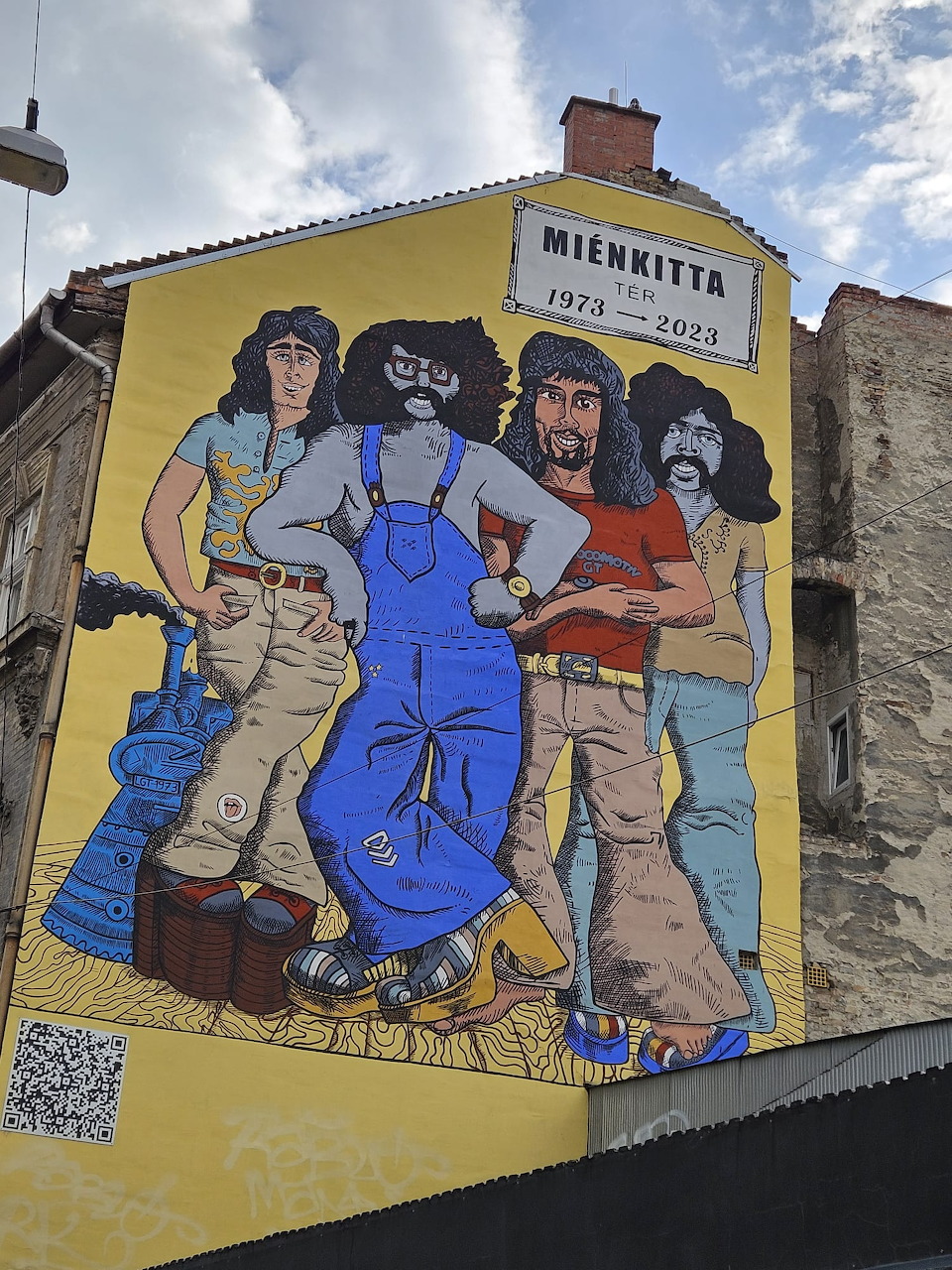 Vibrant street mural of four figures painted on yellow building wall