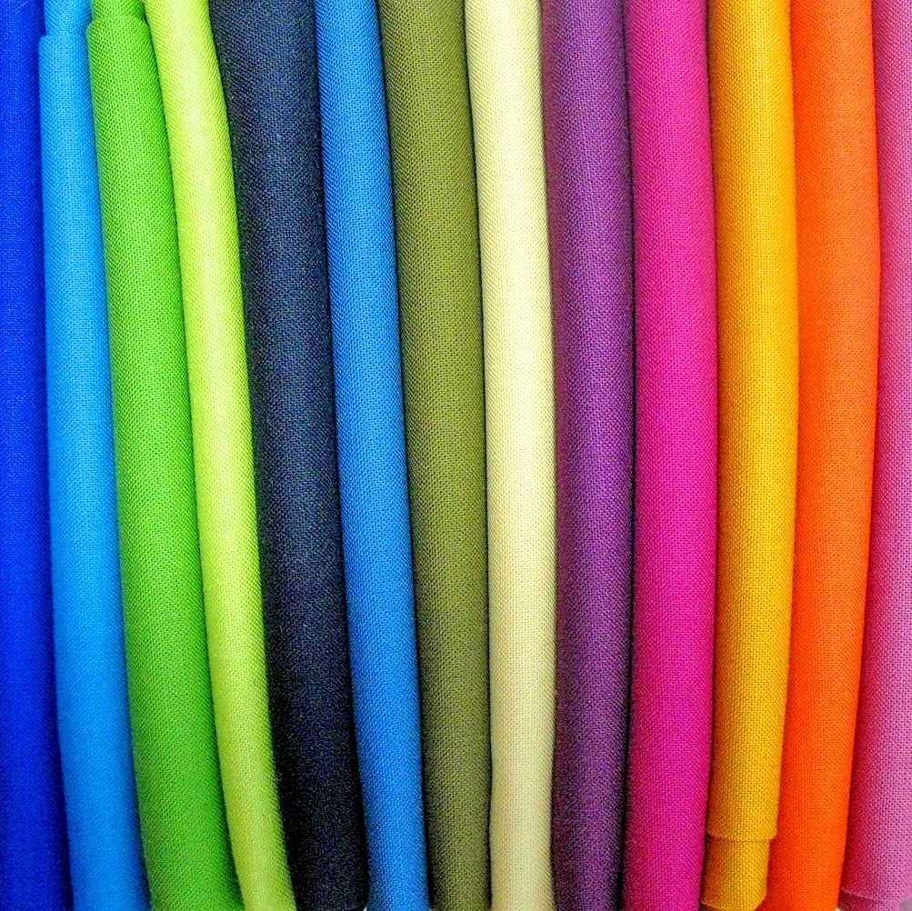 Vertical rows of colorful fabric rolls in rainbow spectrum from blue to pink and orange