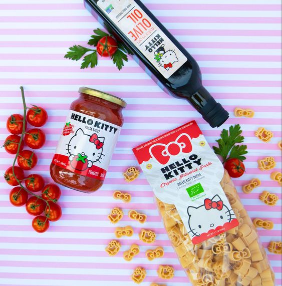 Hello Kitty shaped pasta with tomato sauce, cherry tomatoes, and balsamic vinegar on pink striped background