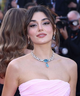 Brunette woman in a strapless pink gown wearing a diamond necklace and earrings at a red carpet event