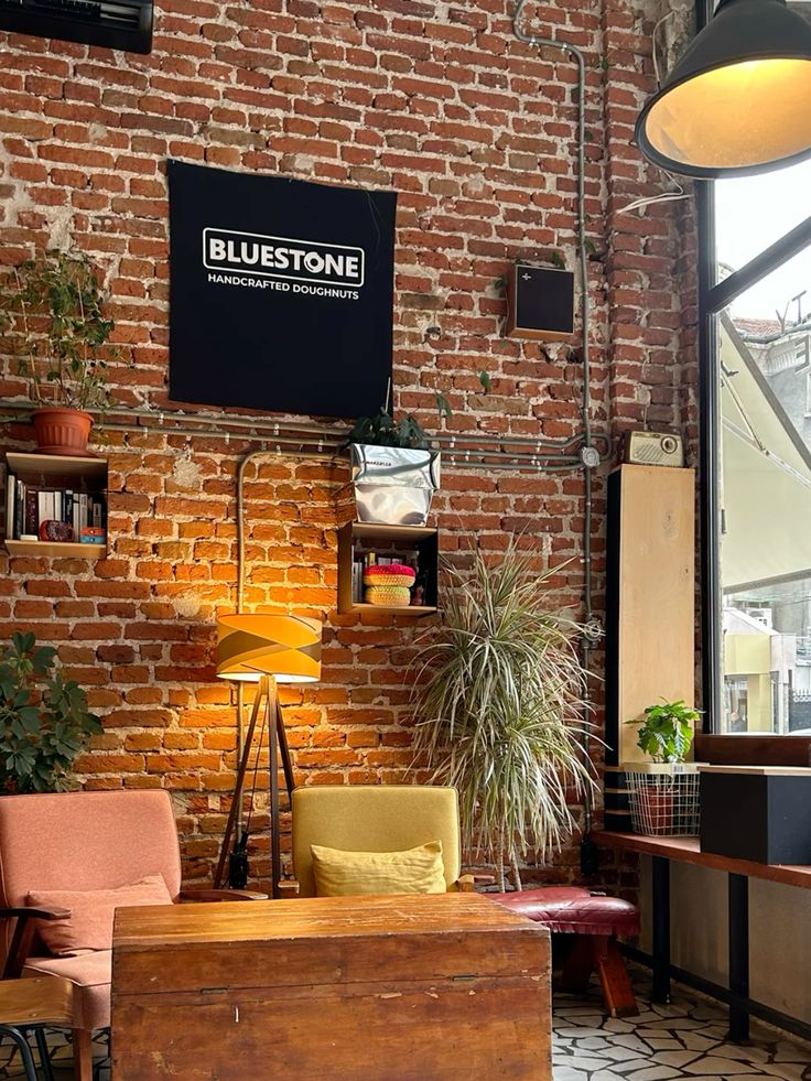 Cafe interior with exposed brick wall, poted plants, wooden table, and industrial pendant lights
