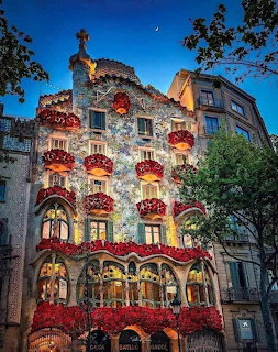 Casa Batlló Barcelona facade lit up at dusk with red floral decorations and mosaic tiles