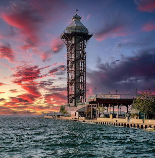Observation tower on waterfront pier at sunset with colorful sky and water