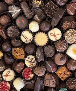 Overhead view of assorted gourmet chocolates with various shapes, toppings, and decorations filling the frame