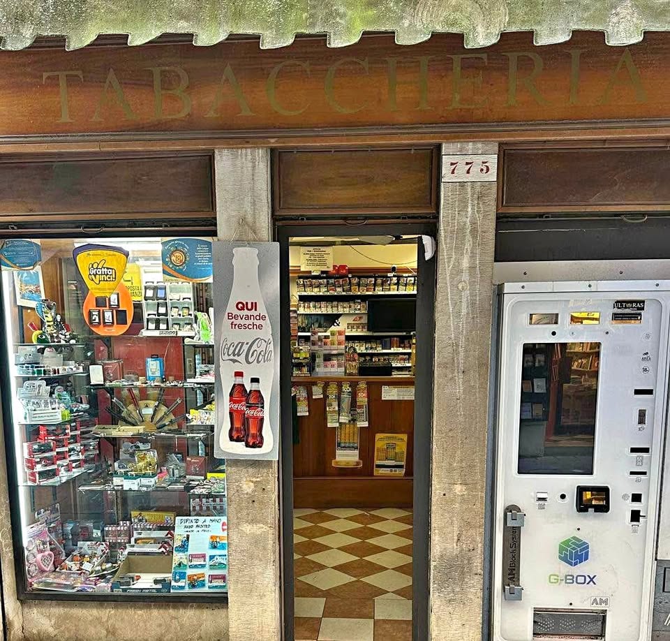 Front of a Venice tobacco shop with souvenir window, open entrance, and vending machine