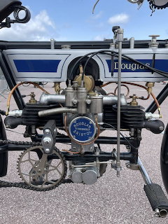 Front view of 1911 Douglas Model D motorcycle engine with brass carburetor and badge