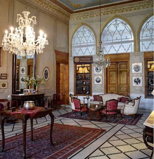 Elegant historic mansion interior with crystal chandelier, arched windows, antique furniture and Persian rugs