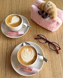 Flat lay of two cappuccinos, glasses, and a pink bag in coquette style.