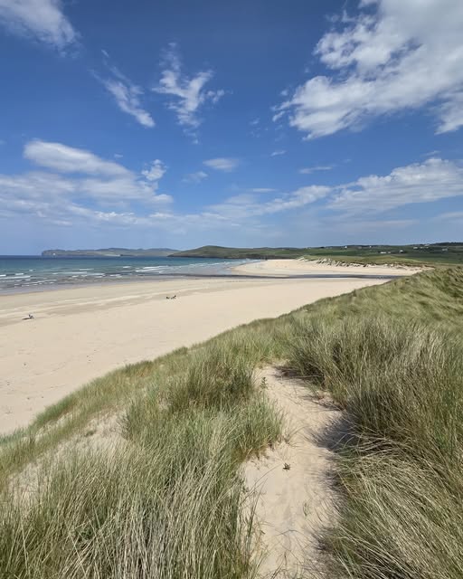 Sandy path through dune grass leading to Falcarragh Beach with ocean and blue sky