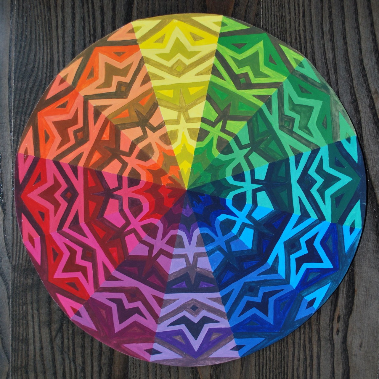 Circular rainbow mandala with geometric patterns on weathered wood surface