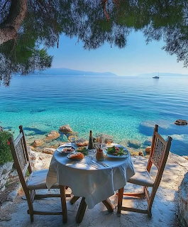 Table for two on stone terrace overlooking turquoise sea with Greek islands in distance