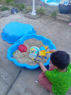 Child playing with toys in blue shell sandbox outdoors