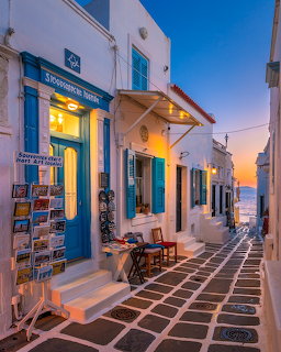 Narrow Greek island alley with whitewashed buildings and blue doors at sunset