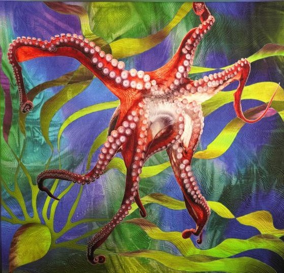 Red octopus with white spots on tentacles, quilted fabric art with blue and green swirling background