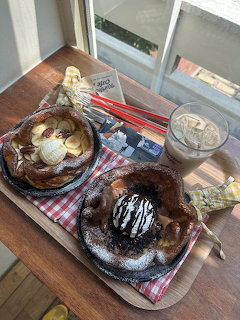Two pastries and an iced coffee on a tray by a sunlit window