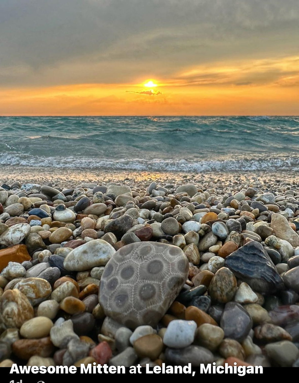 Close-up of Petoskey stones on a pebble beach with sunset over Lake Michigan waves