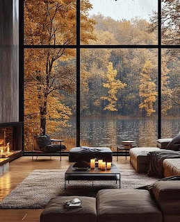 Modern living room with large windows showing autumn trees and a lake outside