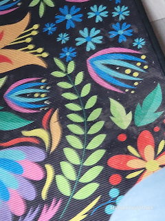 Colorful folk art floral pattern on dark fabric with bright leaves, flowers, and botanical designs