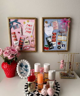 Vanity desk with pink roses, candles, perfumes, jewelry holder, and two decorative pin boards on the wall