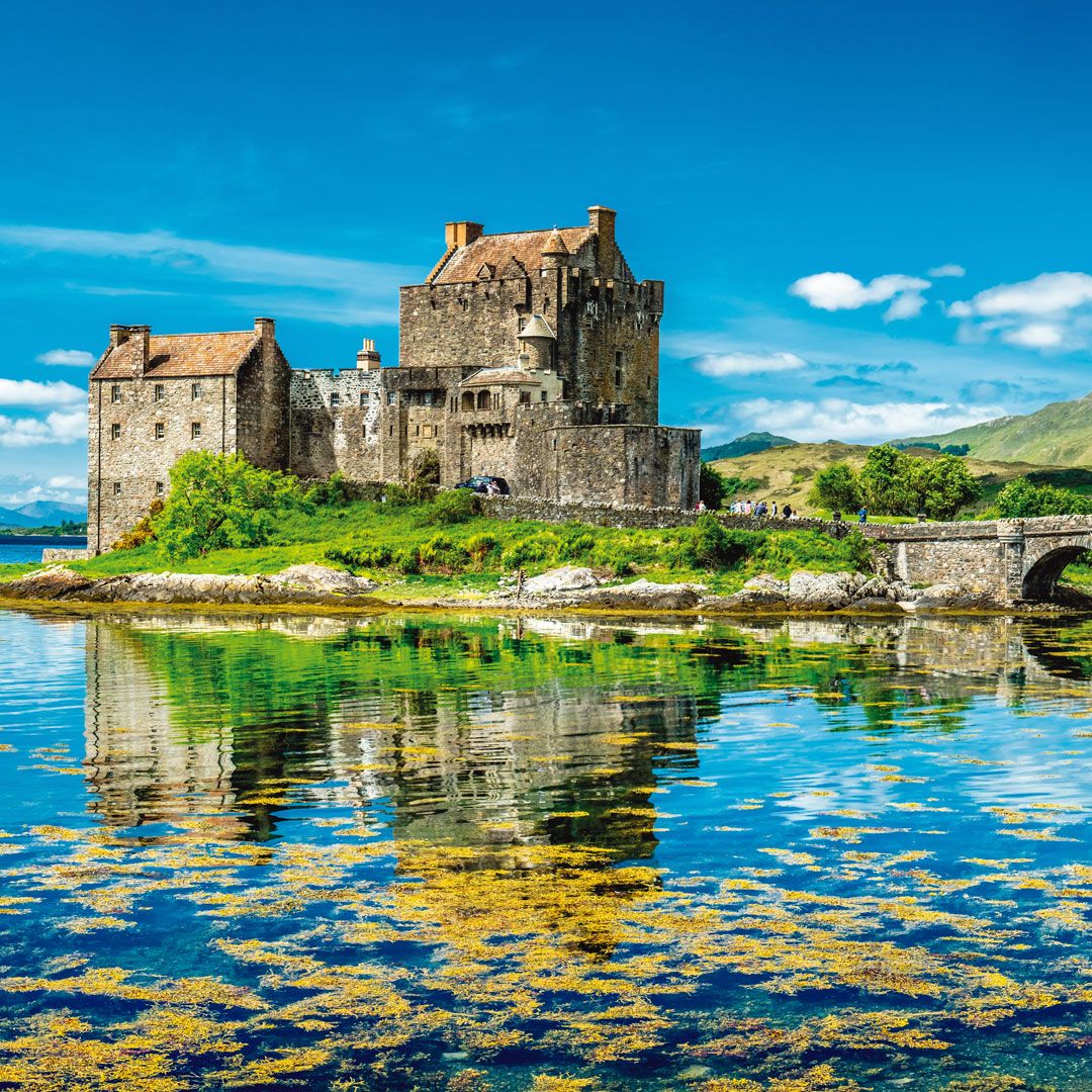 Stone castle on island with water lily reflections under blue sky