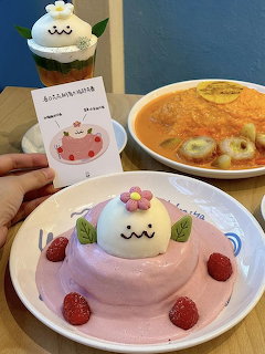 Pompompurin character dessert plate with strawberries and pink cream, curry rice bowl, and themed drink at cafe table
