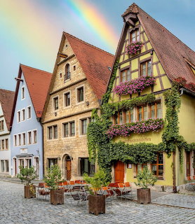 Historic houses on a cobblestone street in Rothenburg ob der Tauber with flowers and a rainbow