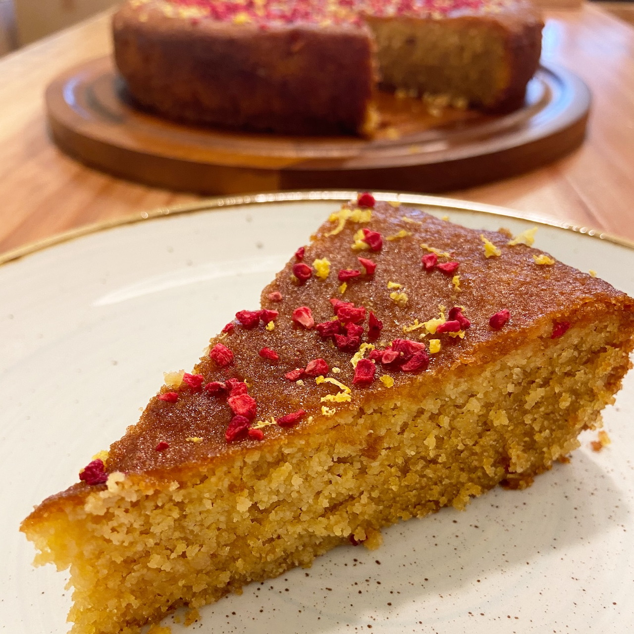 Slice of golden cake with red and yellow sprinkles on a white plate