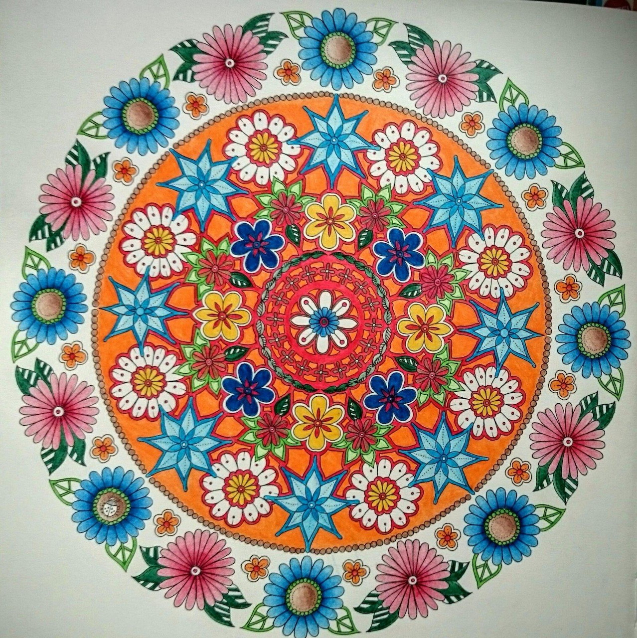 Circular mandala with colorful geometric flower patterns radiating from center in orange, blue, pink and white