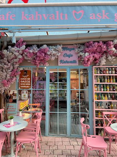 Cafe exterior with pink chairs, tables, and pink flower decorations around the entrance