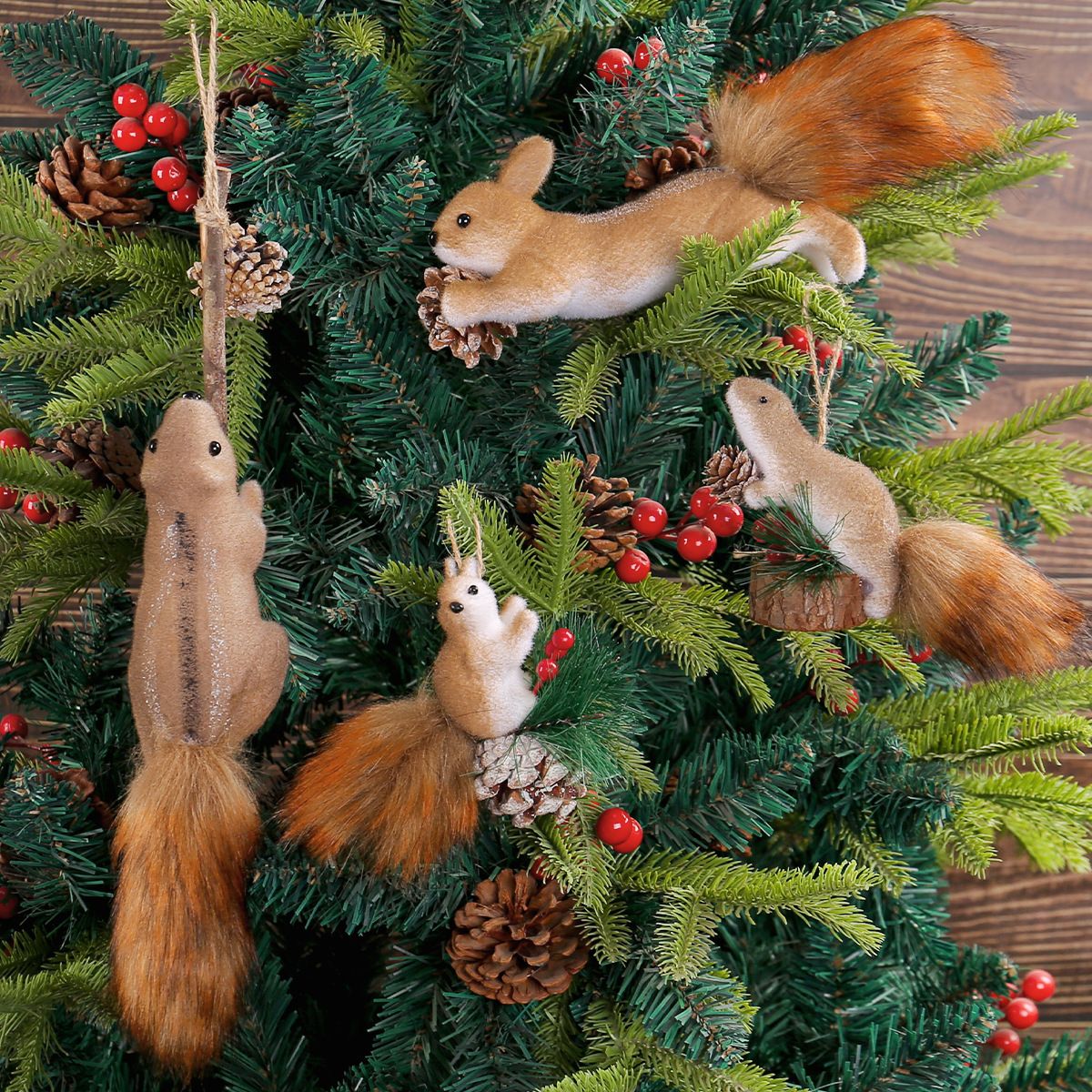 Four ornamental squirrels positioned on pine branches with red berries and pine cones in Christmas wreath arrangement