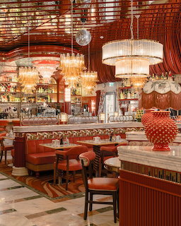 Luxurious restaurant interior with crystal chandeliers, red velvet seating, marble bar, and ornate decor