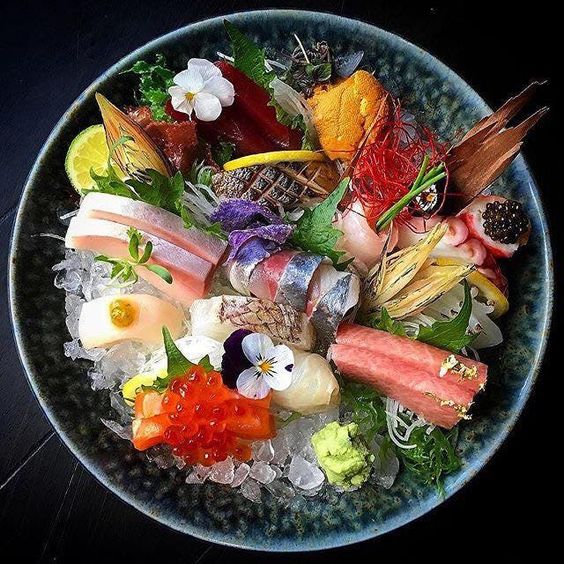 Overhead view of elaborate sashimi bowl with tuna, salmon, roe, and various seafood arranged decoratively on rice