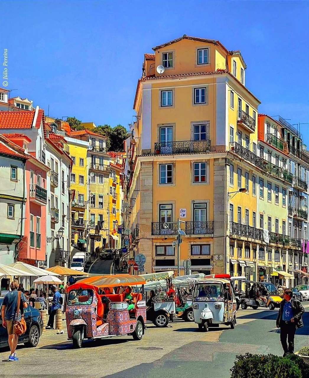 Colorful buildings on a street in Lisbon with tourists and a sightseeing tram