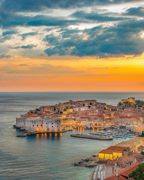 Dubrovnik old town at sunset on the Adriatic coast with glowing buildings and cloudy sky
