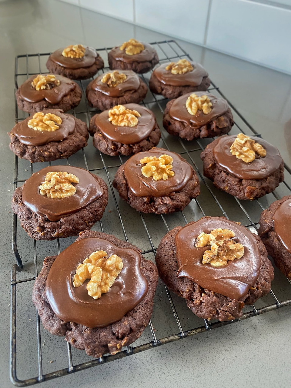 Chocolate Afghan biscuits with icing and walnut halves on a wire cooling rack
