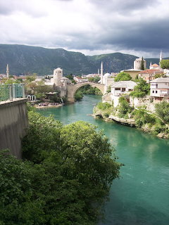 Mostar's famous stone bridge over turquoise river with historic buildings and mountains