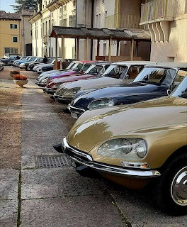 Row of vintage cars parked along a wet street beside a building