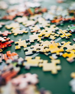 Colorful jigsaw puzzle pieces scattered on a green table surface