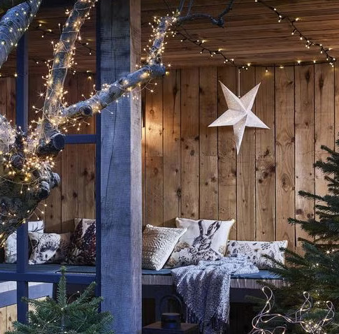 Rustic wooden porch with Christmas star, fairy lights, and cozy textiles