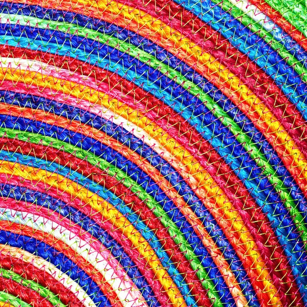 Close-up of colorful woven sisal material showing rainbow striped texture with braided fiber pattern