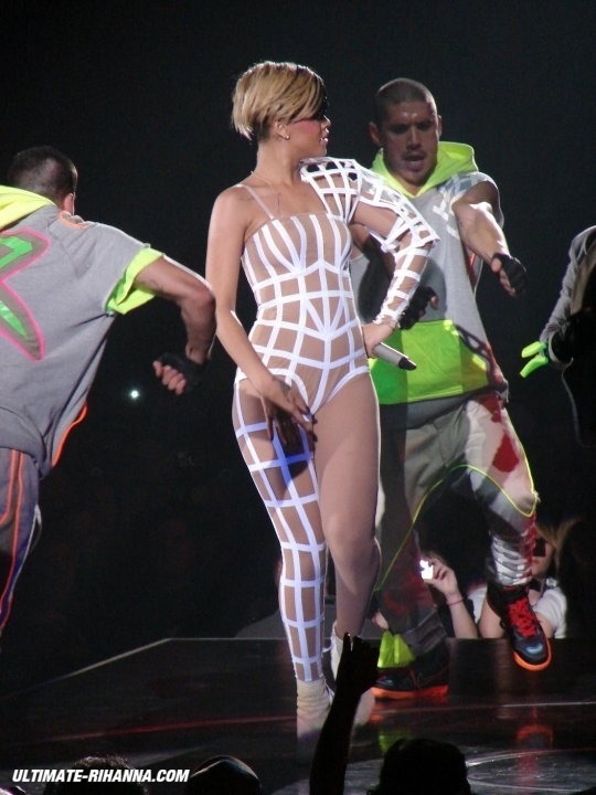 Rihanna singing on stage under bright stage lights during a live concert performance.