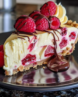 Slice of raspberry cheesecake with chocolate drizzle and fresh raspberries on top