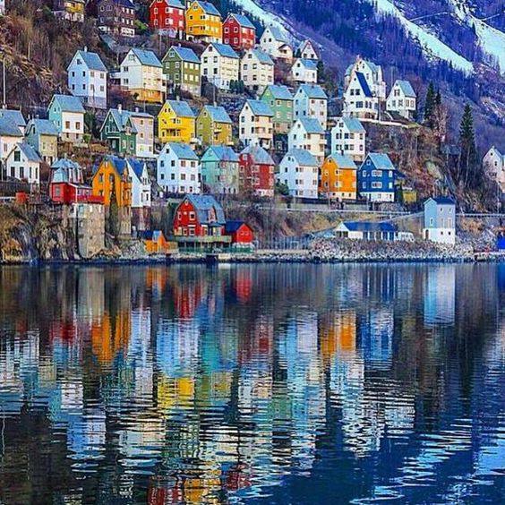 Colorful houses on a hillside in Odda, Norway, reflected in still water