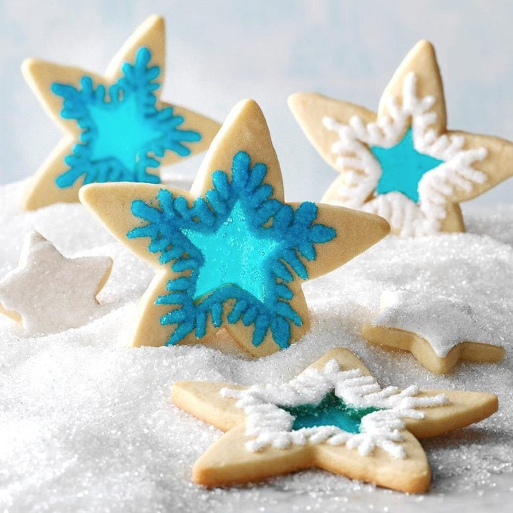 Star-shaped cookies with blue translucent candy centers resembling stained glass, dusted with powdered sugar