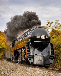 Norfolk & Western 611 steam locomotive running through fall foliage with large black smoke plume