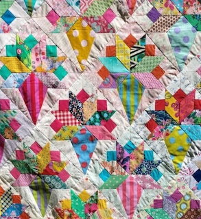 Close-up of a patchwork quilt with repeating cone-shaped fabric pieces in multiple colors.